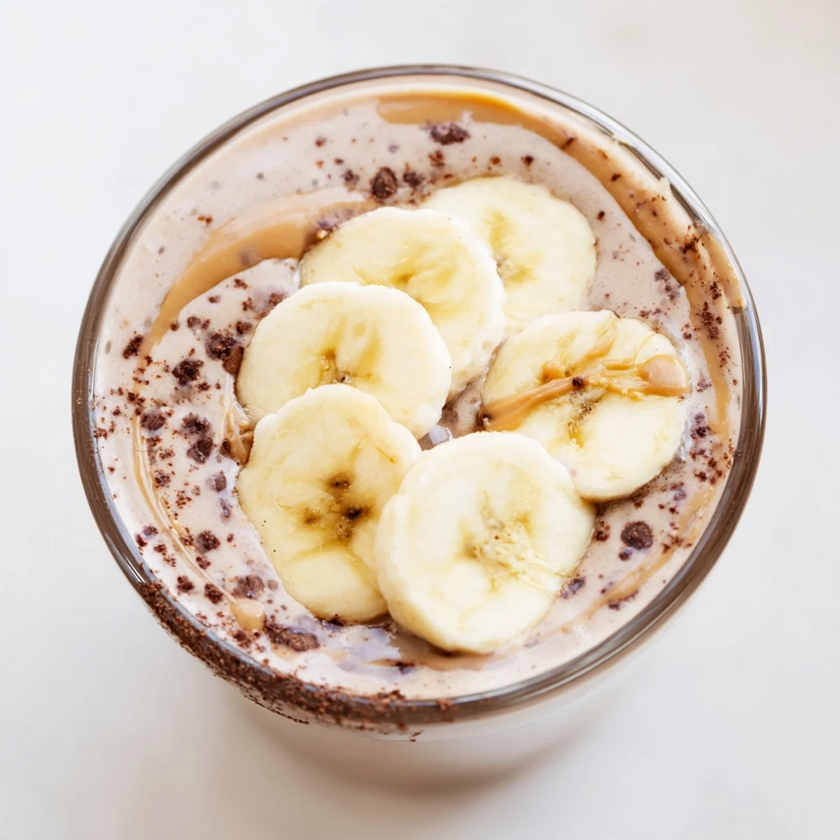 Glossy glass filled with a thick, creamy Chocolate Peanut Butter Smoothie topped with a fresh banana slice, ready to sip.