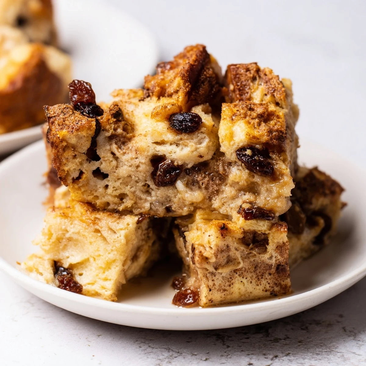 Homemade bread pudding with raisins, baked to golden perfection and paired with a dollop of whipped cream.