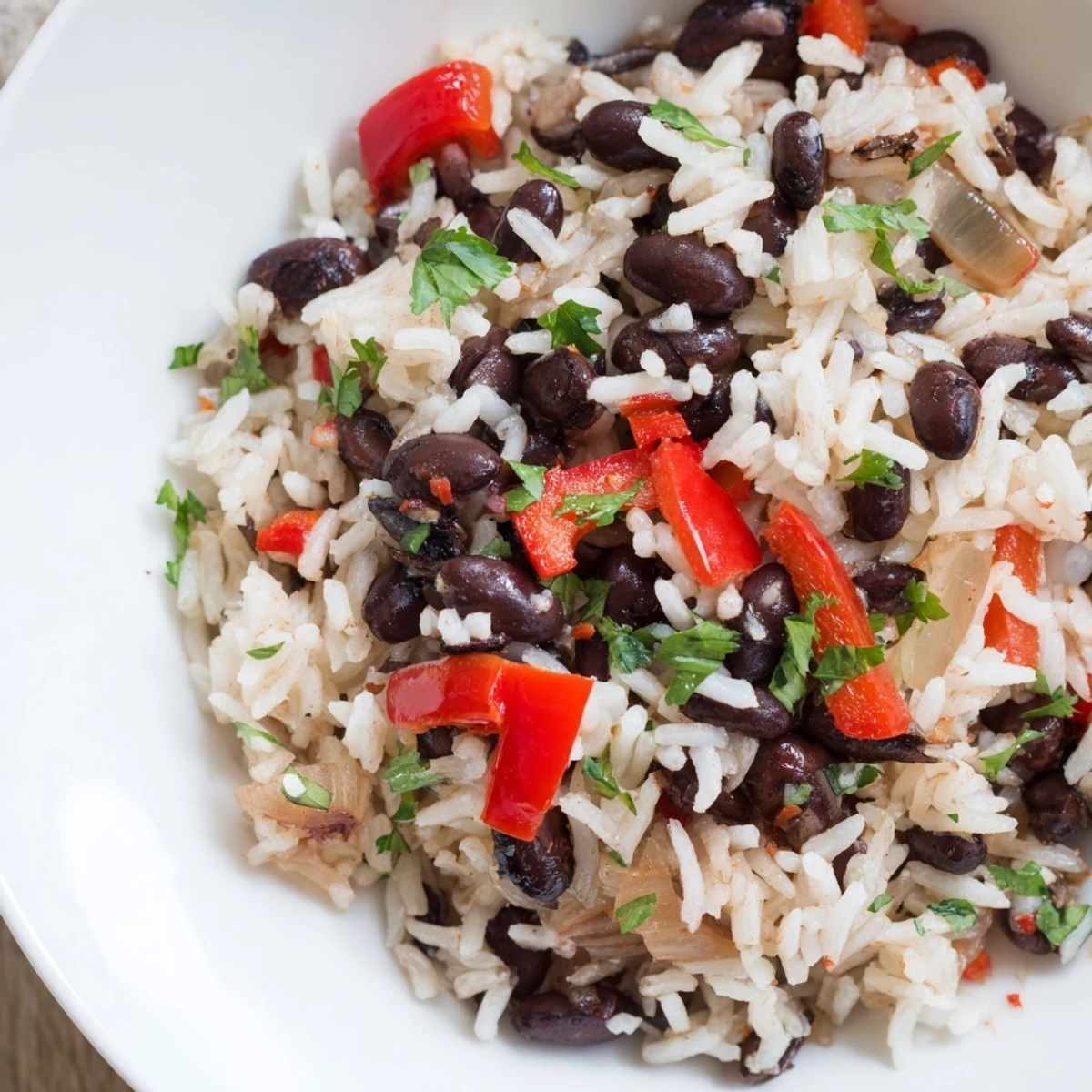 Fork-tender Rice and Beans with Spices in a white bowl, garnished with fresh cilantro and a lime wedge, ideal for a cozy vegetarian dinner.