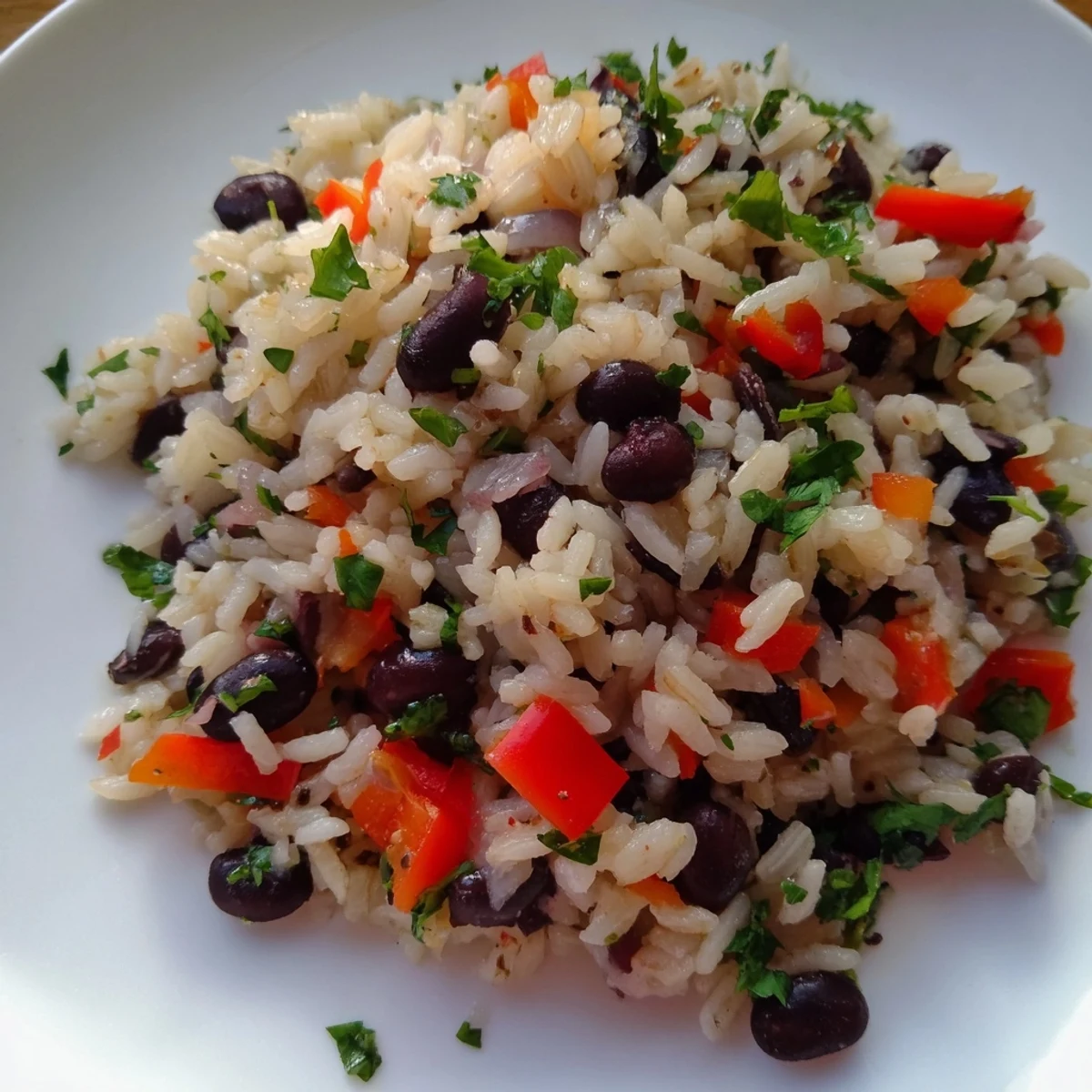A skillet of hearty Rice and Beans with Spices next to chopped cilantro and lime wedges for serving.