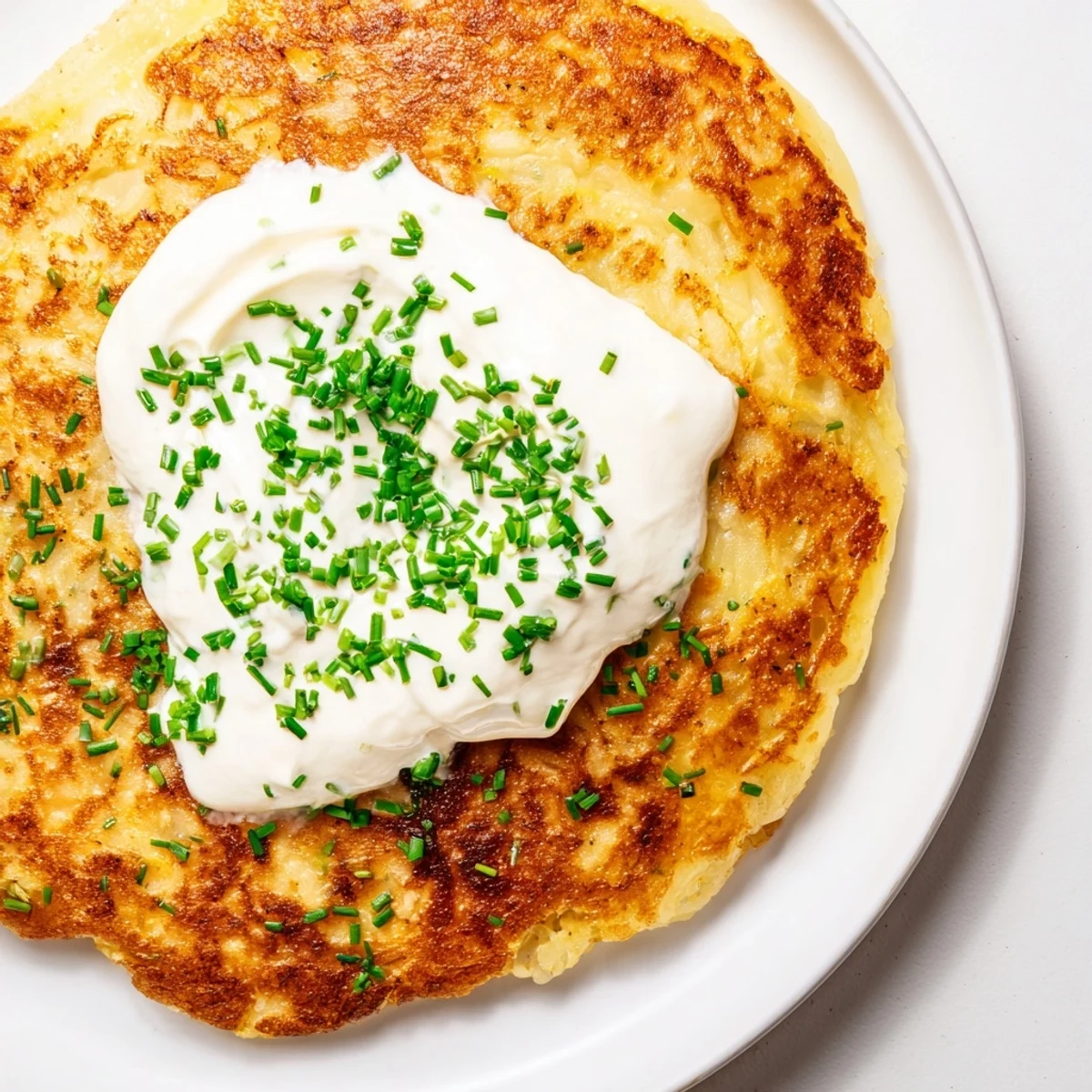 Golden-brown Irish Boxty with Sour Cream, crispy on the outside and tender inside, topped with a dollop of creamy sour cream and fresh chives, served hot.