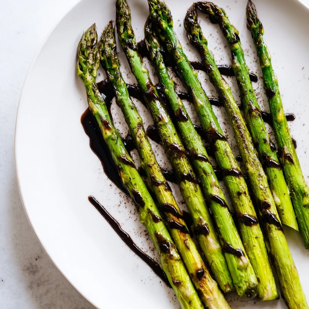 Vivid close-up of oven-roasted asparagus with balsamic glaze, finished with fresh black pepper, perfect for easy, healthy weeknight meals.