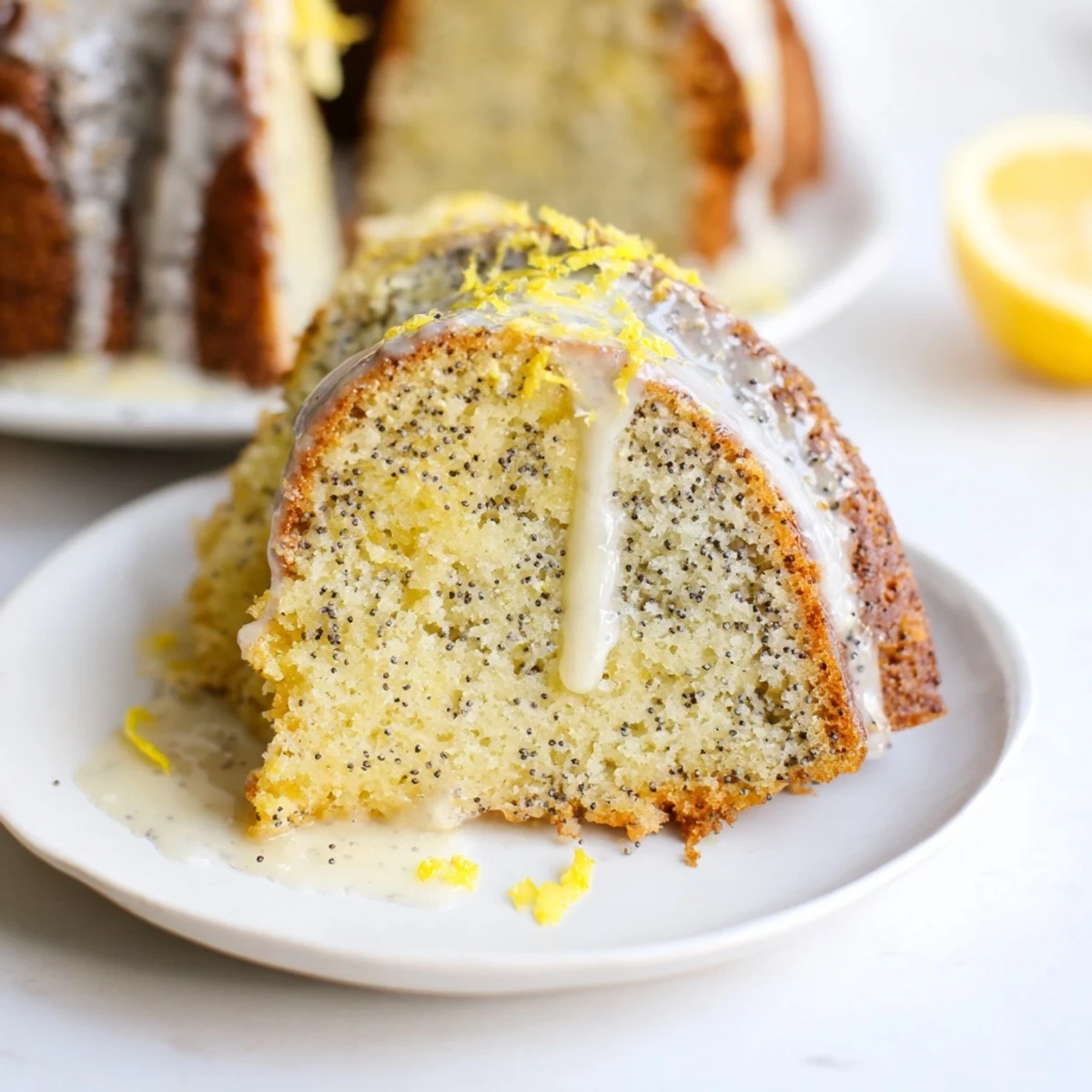 A golden bundt cake drizzled with Lemon Poppy Seed Bundt Cake with Icing, showing a tender slice on a fork.