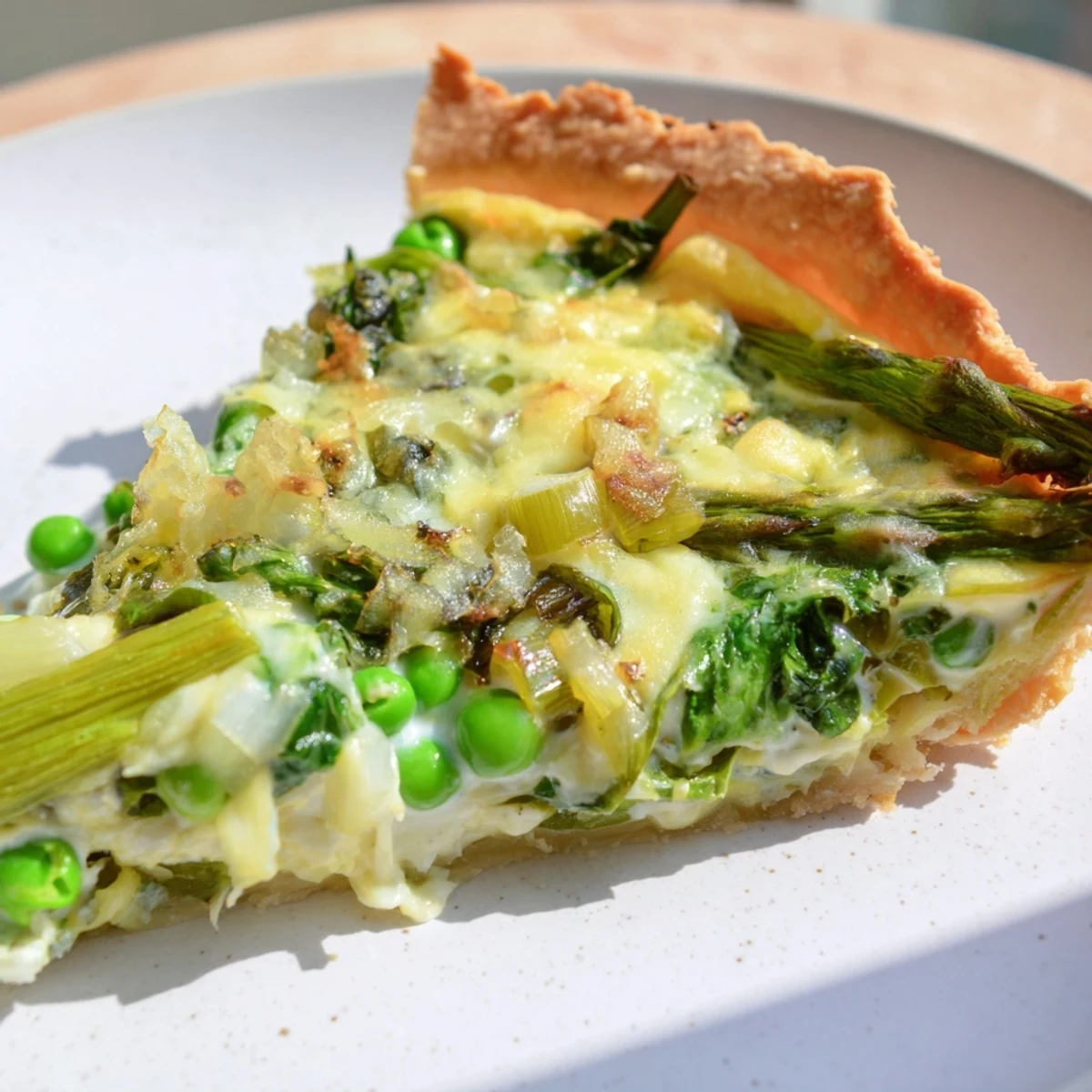 Sliced Spring Vegetable Quiche on a white plate, served warm with a crisp garden salad. 