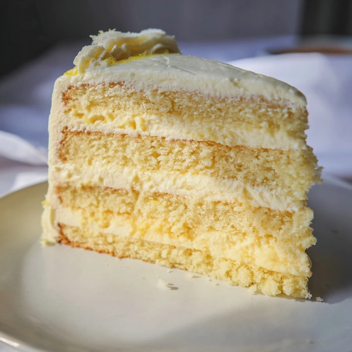 A slice of Limoncello Mascarpone Cake on a plate, showing fluffy layers and mascarpone filling next to a glass of wine.