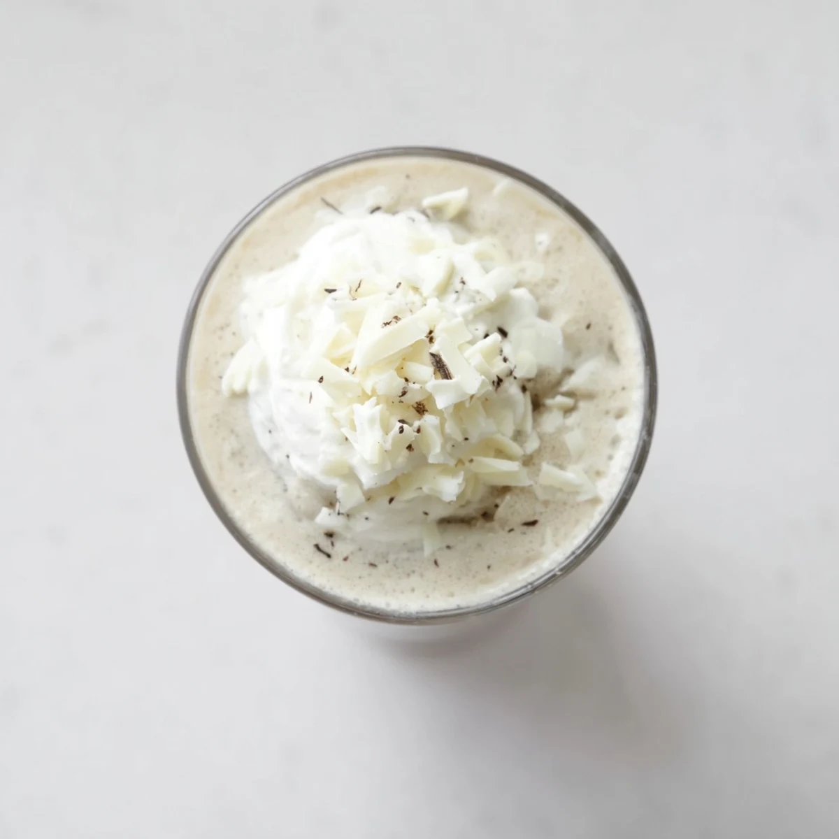 The image shows a creamy Vanilla Bean Frappuccino with white chocolate shavings, perfect for a coffeehouse treat at home.