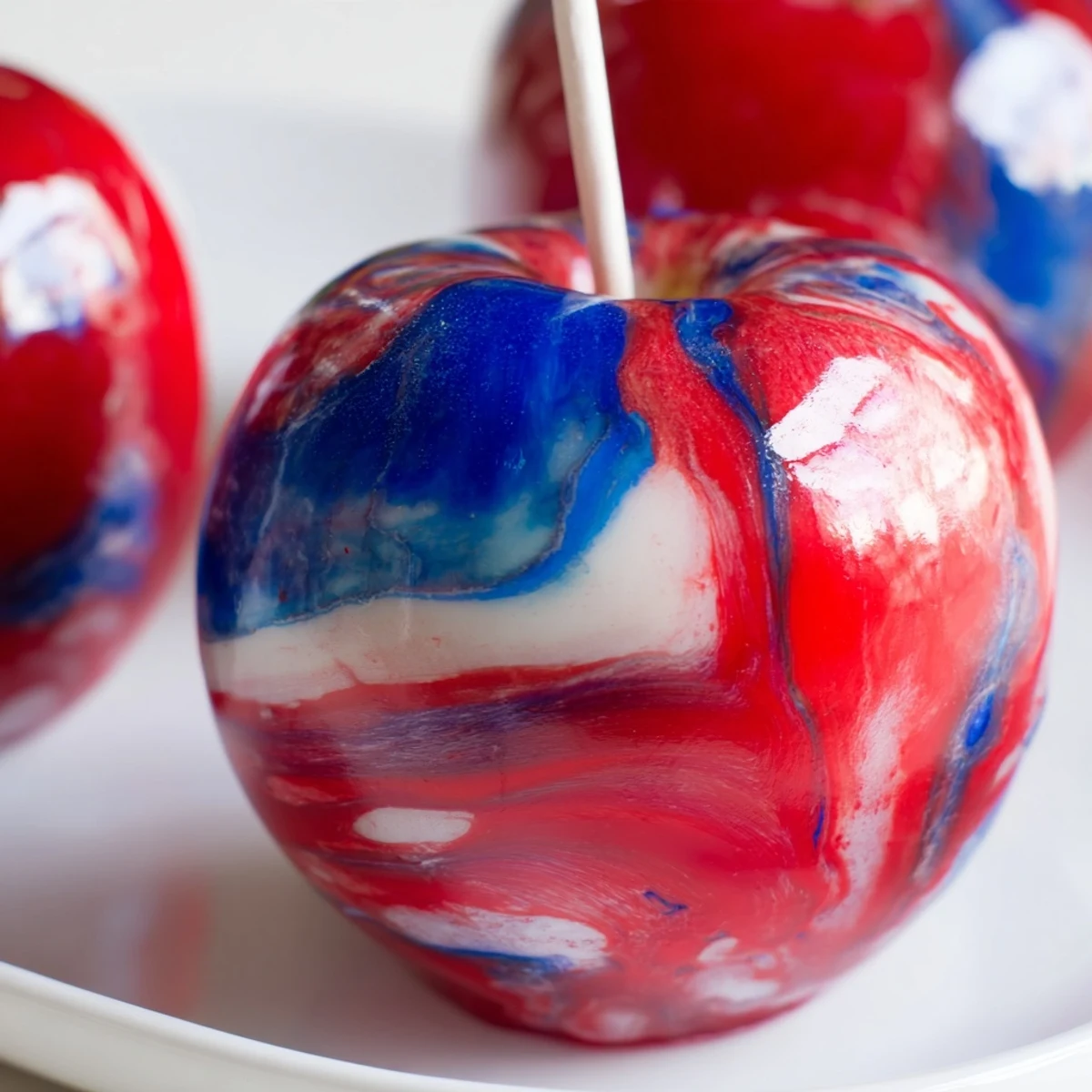 A close-up of Marbled Effect Candy Apples with a vivid red and blue swirl on a glossy candy shell.