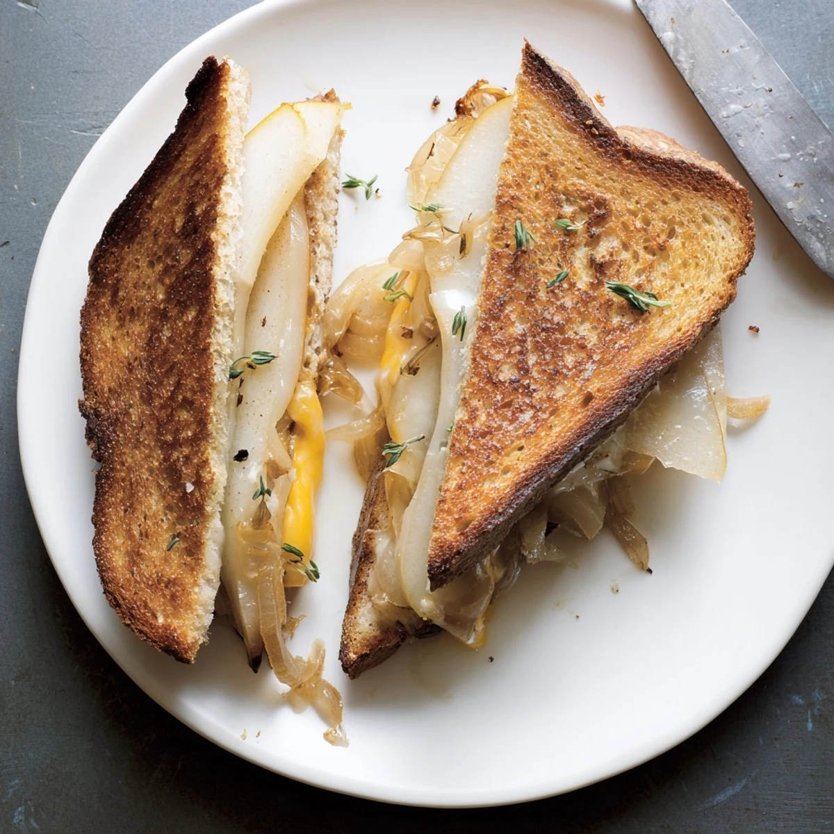 Warm golden slices of Pear, Apple & Grilled Cheese with Caramelized Onions on a plate, showcasing gooey melted cheddar and savory onion jam.
