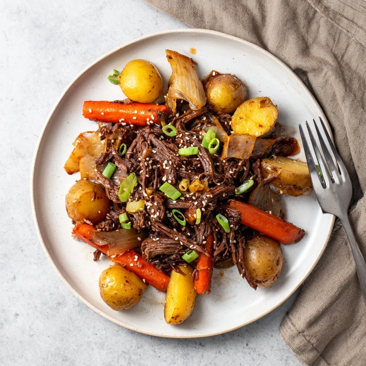 Tender Slow Cooker Korean Beef Pot Roast with soy garlic gravy drizzled over carrots and potatoes.
