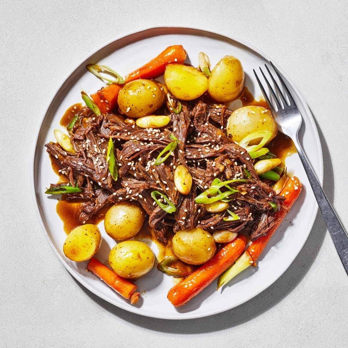 A plate of Slow Cooker Korean Beef Pot Roast alongside steamed rice and sesame seeds.