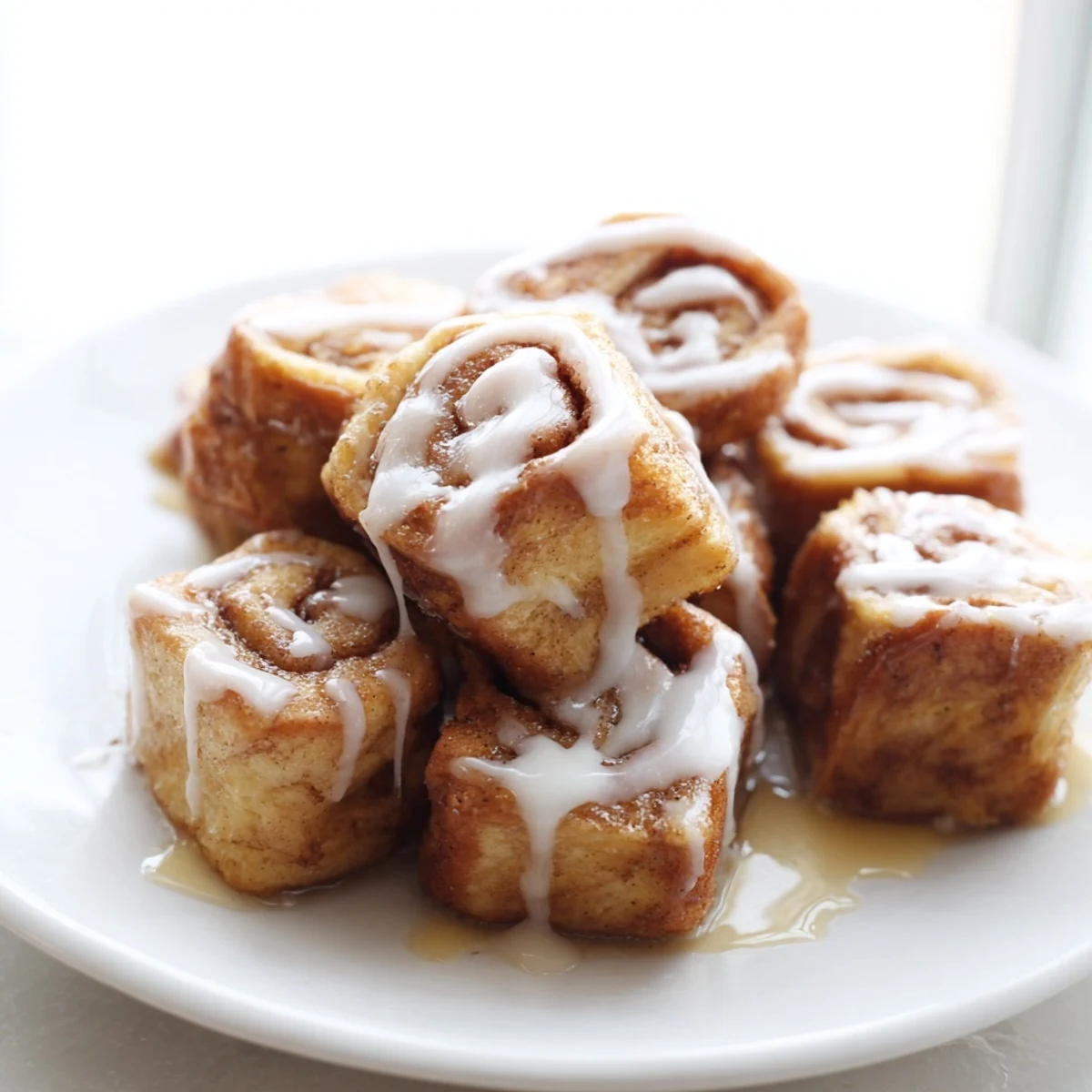 Warm Cinnamon Roll French Toast Bites drizzled with maple syrup on a wooden board for a cozy brunch.