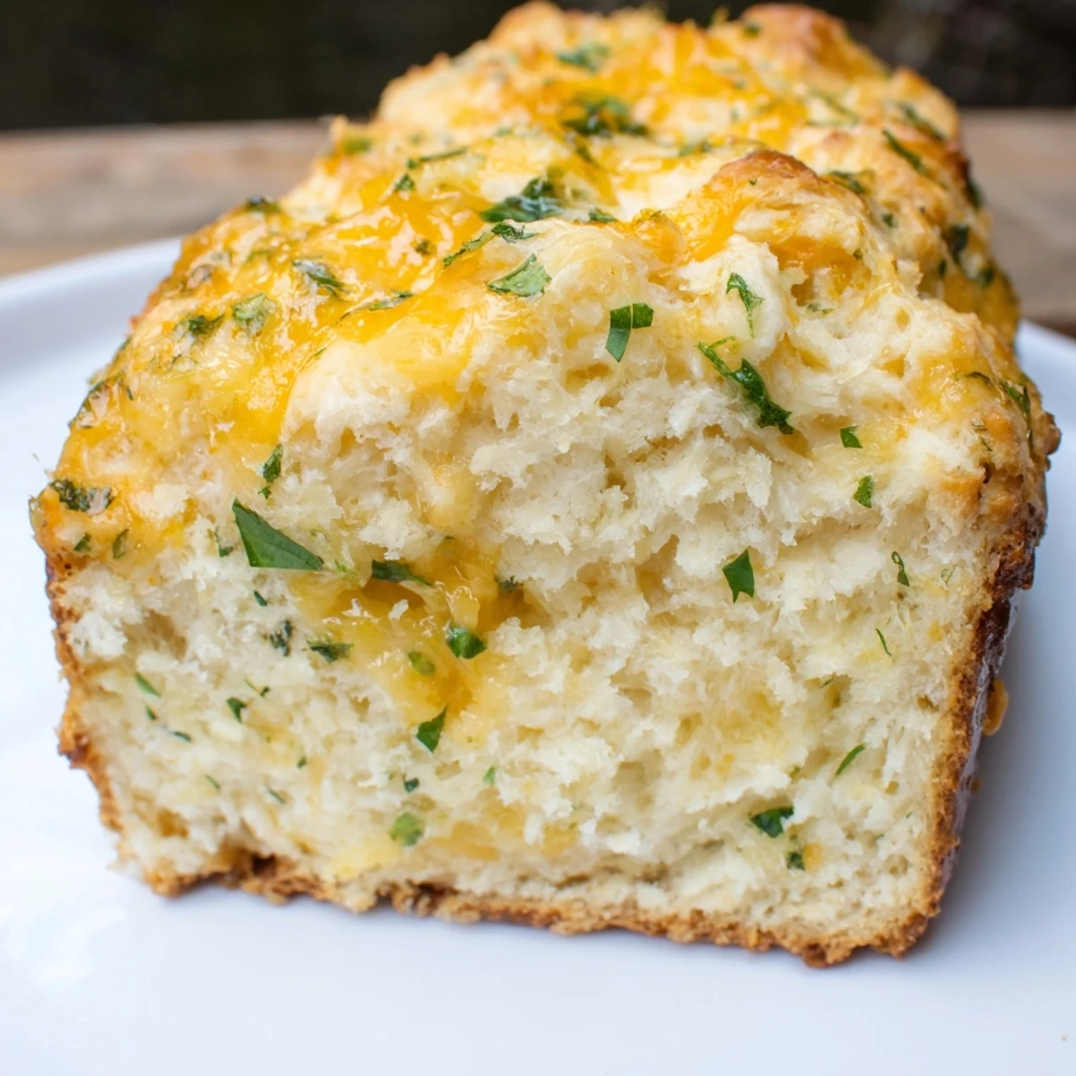 Golden-brown Red Lobsters Cheddar Bay Biscuit Loaf sliced to show fluffy interior studded with sharp cheddar and fresh parsley.