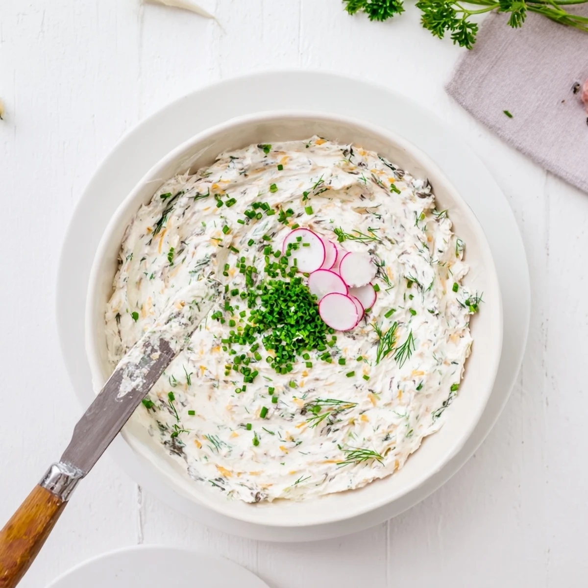 Freshly made Simple Easter Herb Cheese Dip served with crunchy crackers and vegetable sticks on a wooden board.