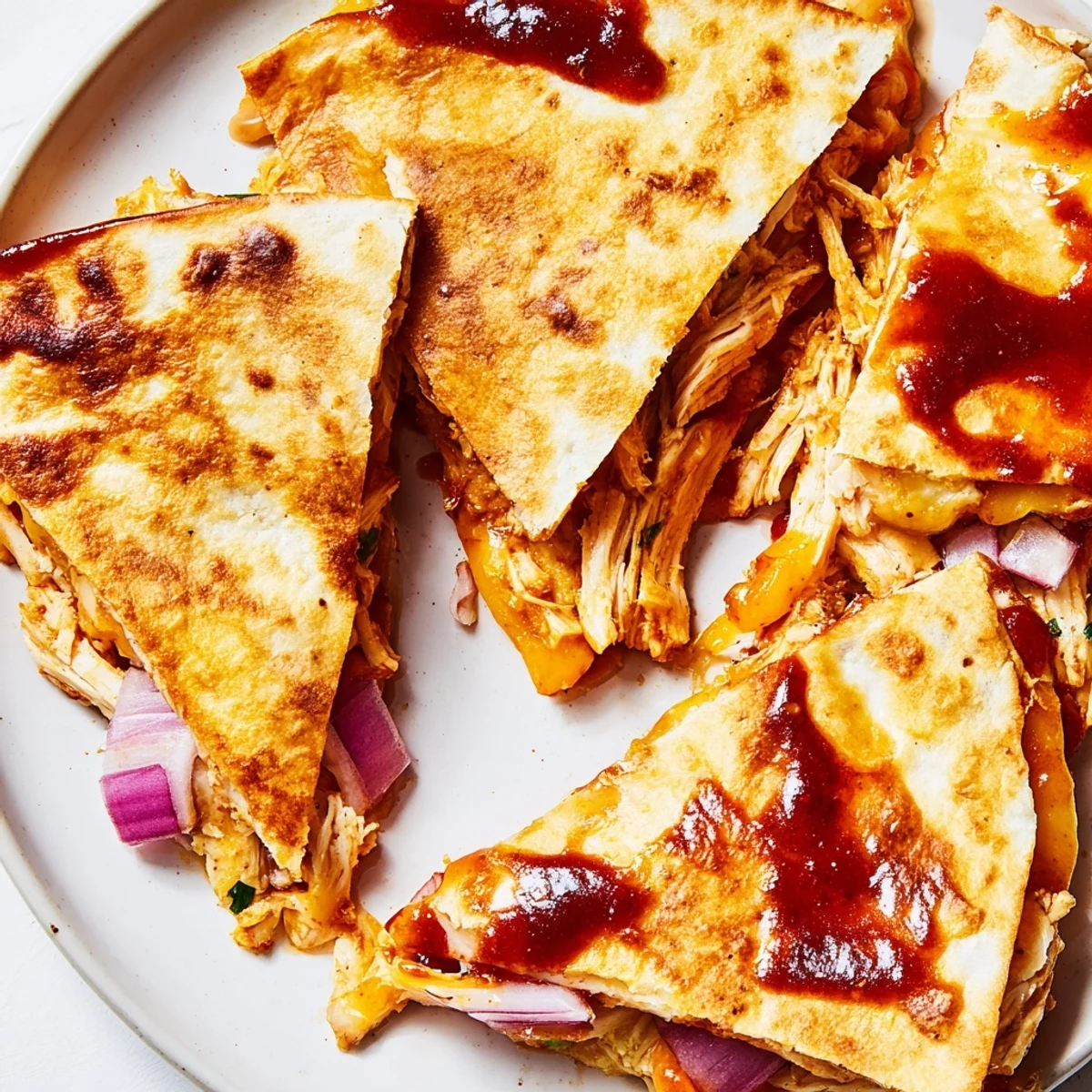 Close-up of crispy hot honey BBQ chicken quesadilla wedge revealing tender shredded chicken and gooey cheese, served with fresh cilantro and lime wedges.