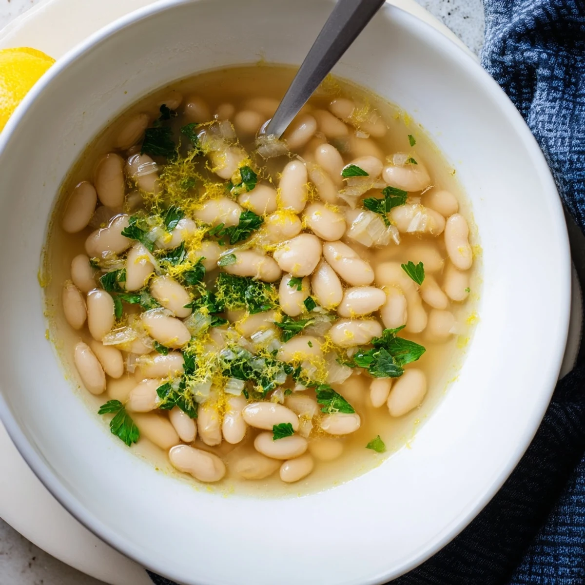 Creamy white beans swimming in golden miso-butter broth topped with fresh green herbs and bright lemon zest