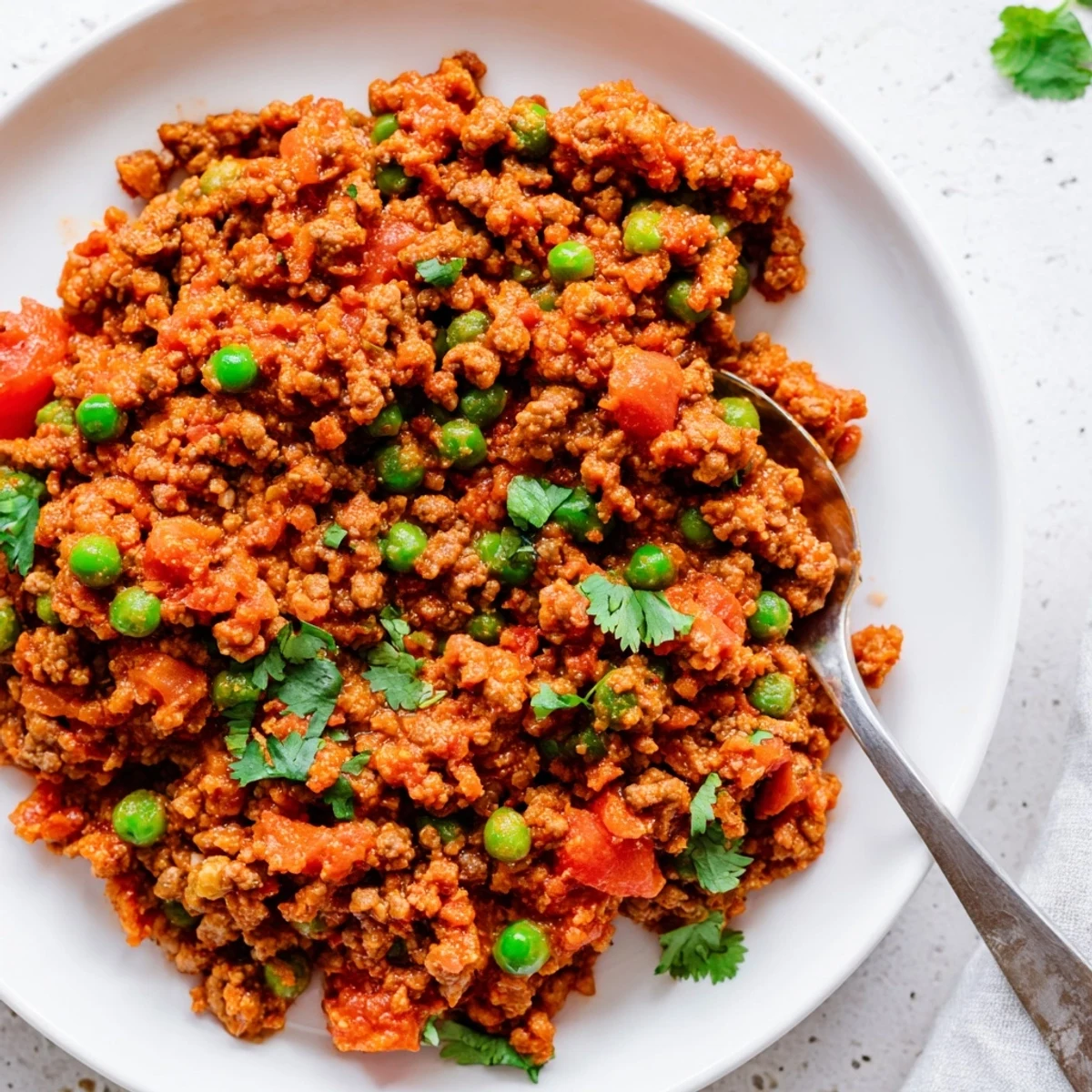 Savory Keema Curry featuring spiced ground beef with vibrant green peas and fresh cilantro garnish