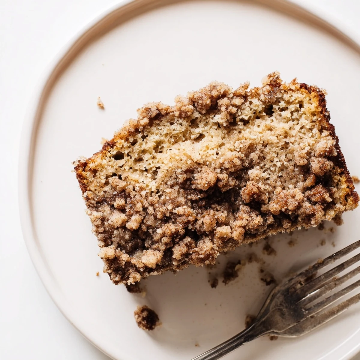 Freshly baked cinnamon crumb banana bread with crunchy spiced topping on wooden cutting board