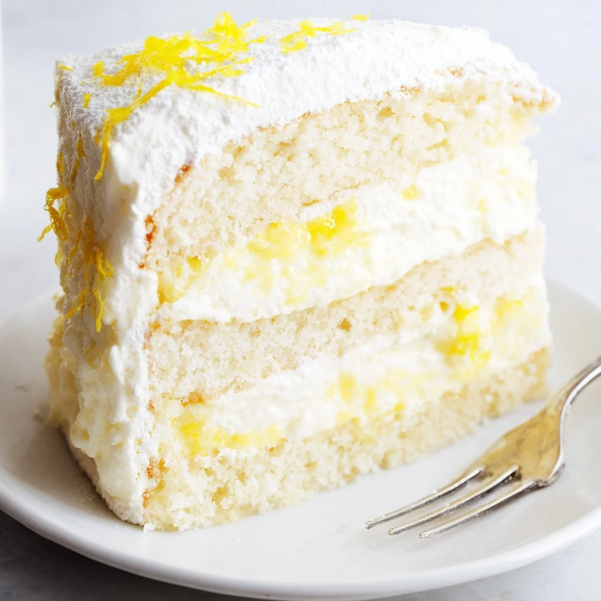 Two-layer Italian lemon cream cake topped with sweet lemon zest and fresh whipped mascarpone frosting