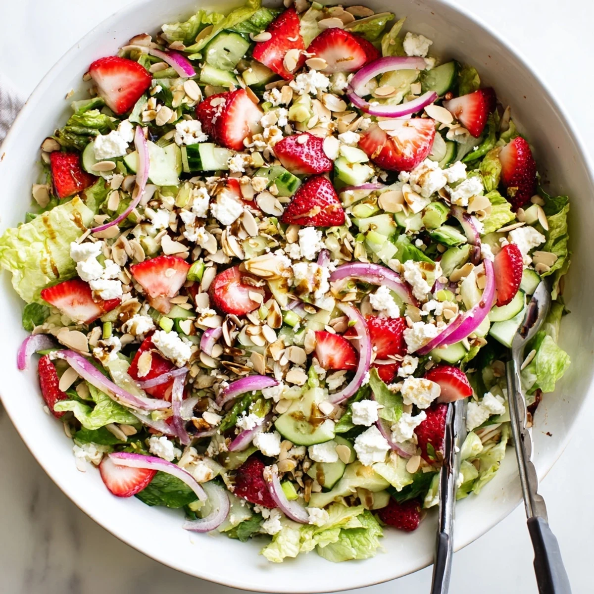 Tossed strawberry romaine feta salad drizzled with balsamic dressing, topped with crunchy toasted almonds