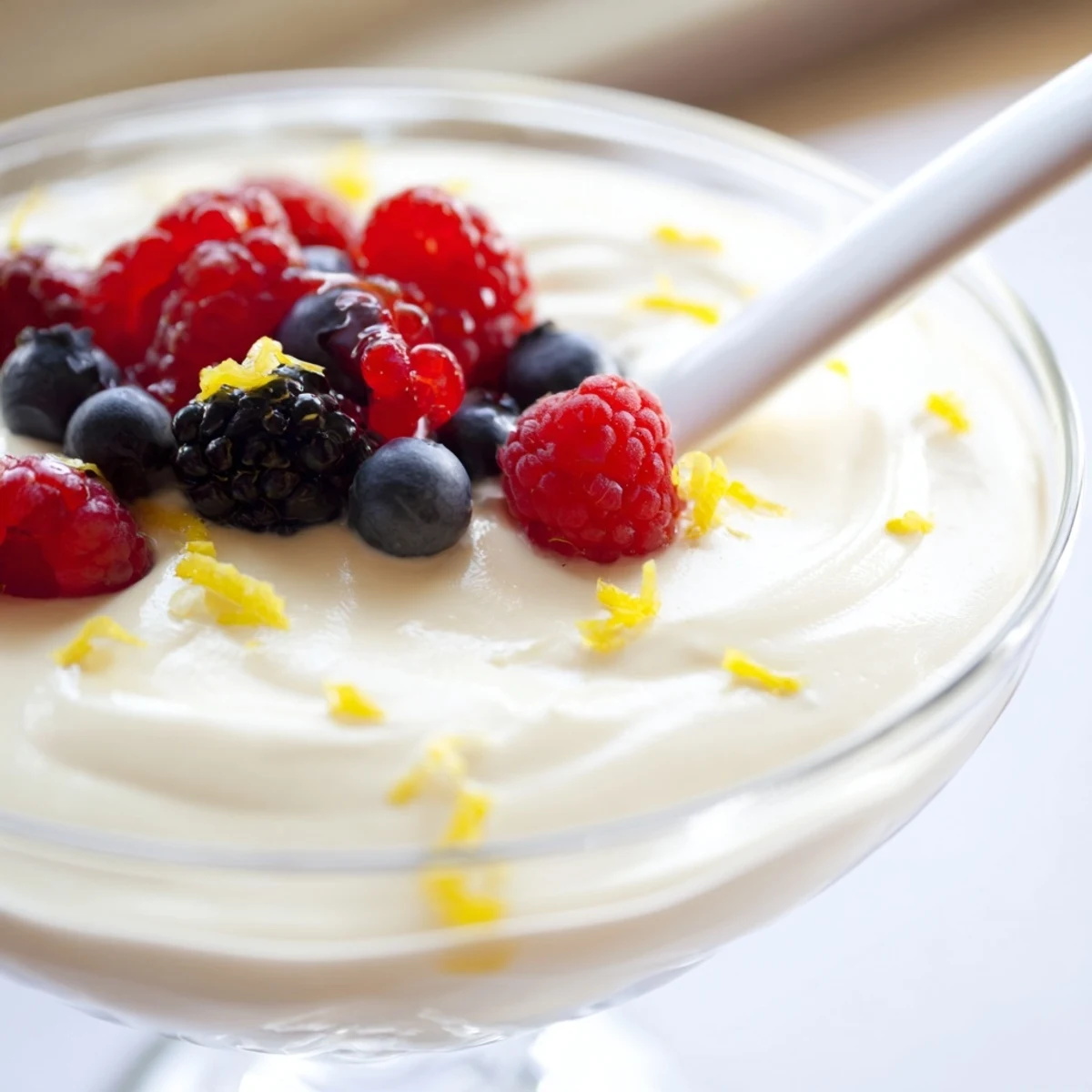Creamy no bake lemon mascarpone mousse topped with fresh berries and mint in clear glass