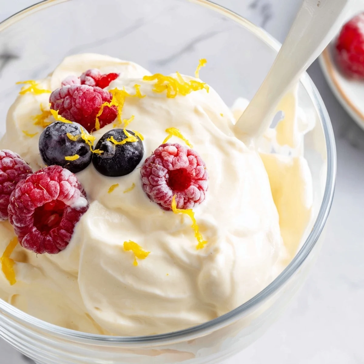 Light and tangy no bake lemon mousse with whipped cream texture and berry garnish