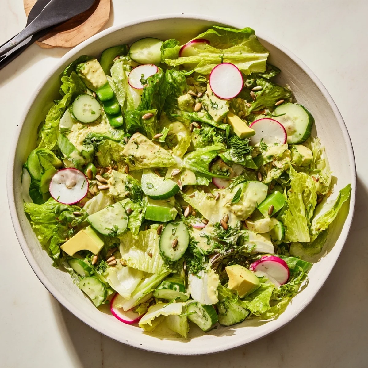 Fresh Green Goddess salad plated with diced avocado, sunflower seeds, and tangy yogurt dressing