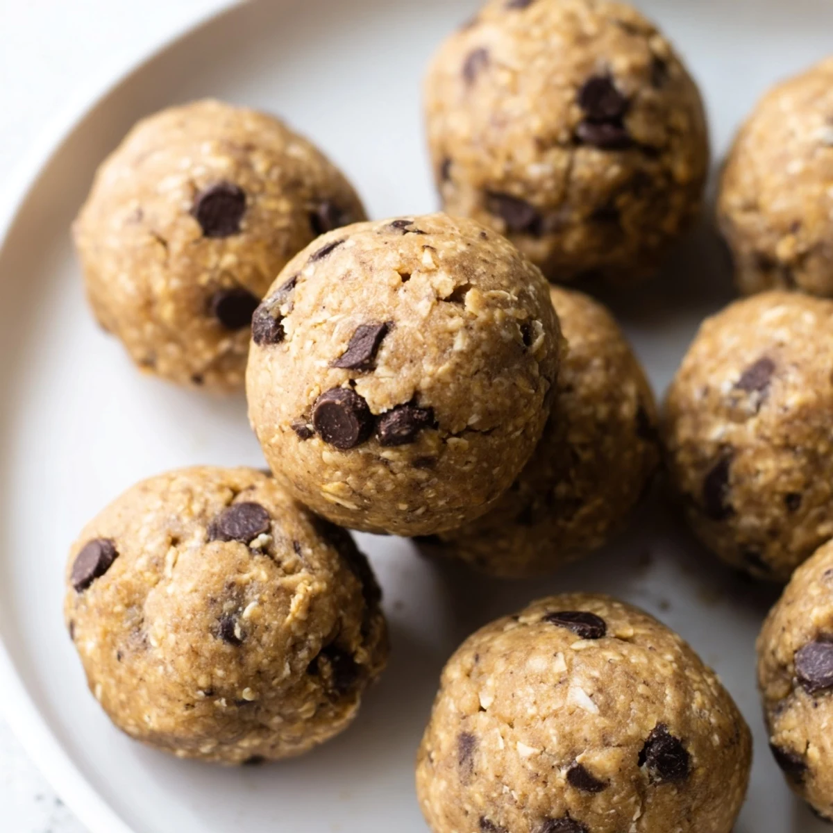 No-bake chocolate chip cookie dough protein balls nestled on a white plate ready for healthy snacking