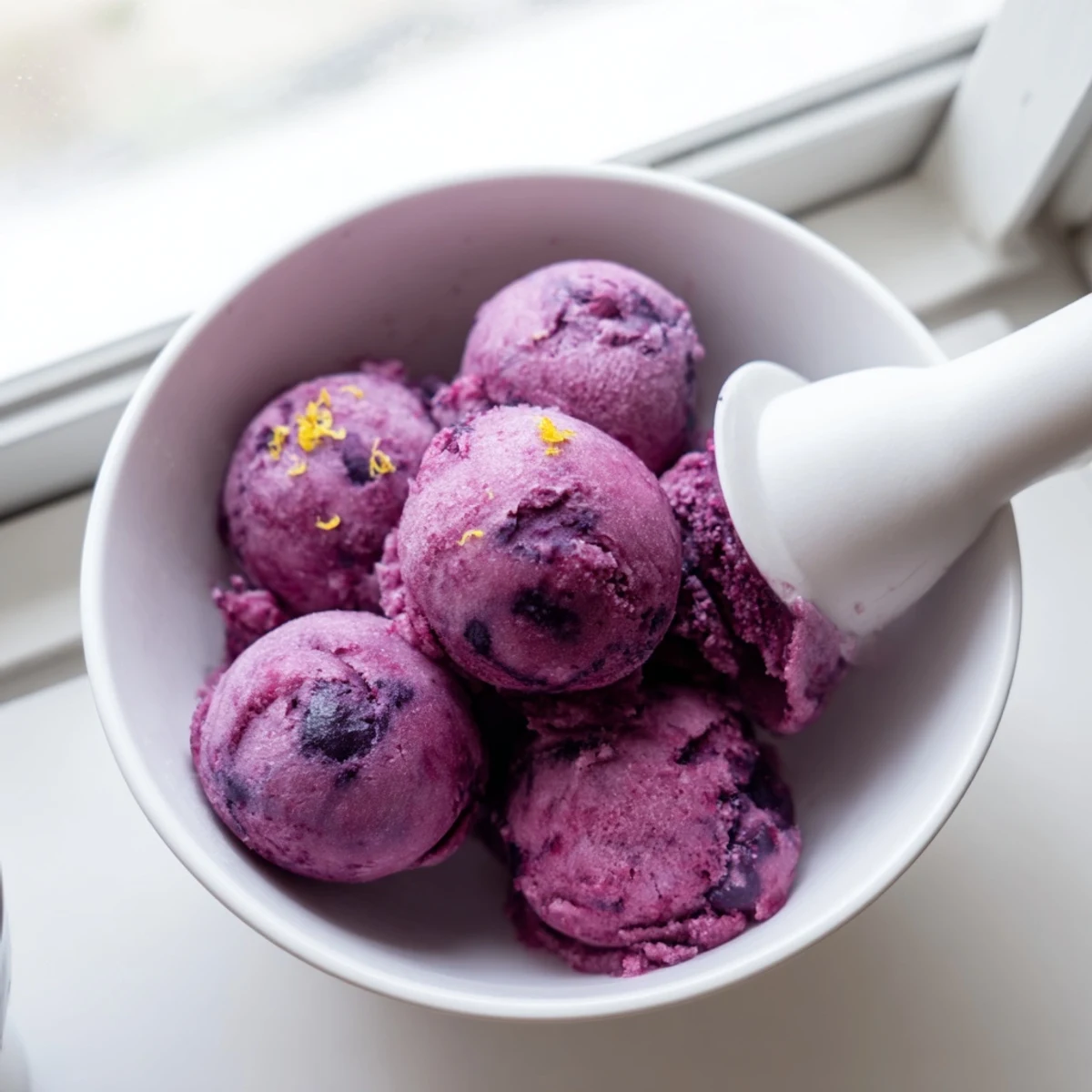 Vibrant purple scoops of no churn blueberry lemon sorbet garnished with fresh mint sprigs