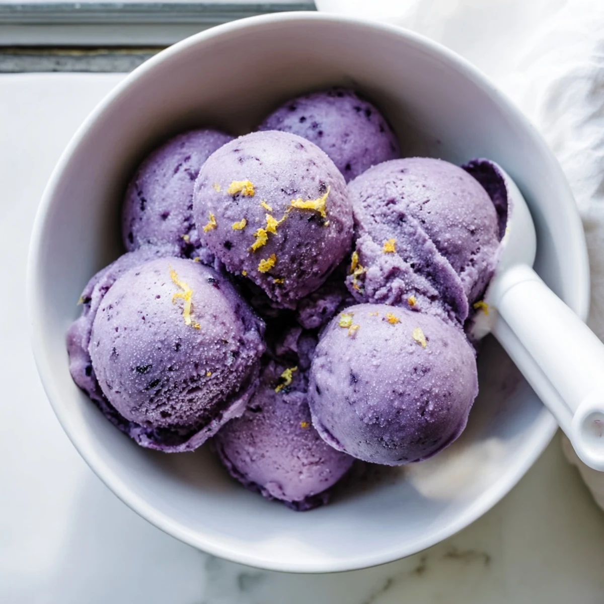 Smooth blueberry lemon sorbet served in chilled bowls with fresh blueberries and lemon zest
