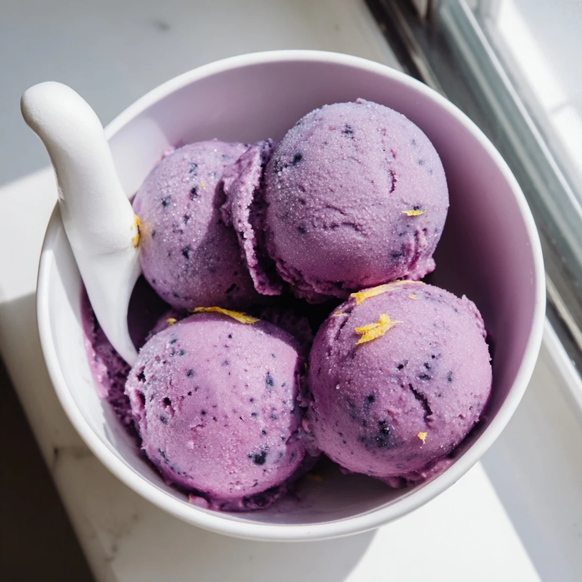 Creamy no churn blueberry lemon sorbet melting slightly in a decorative glass dessert bowl