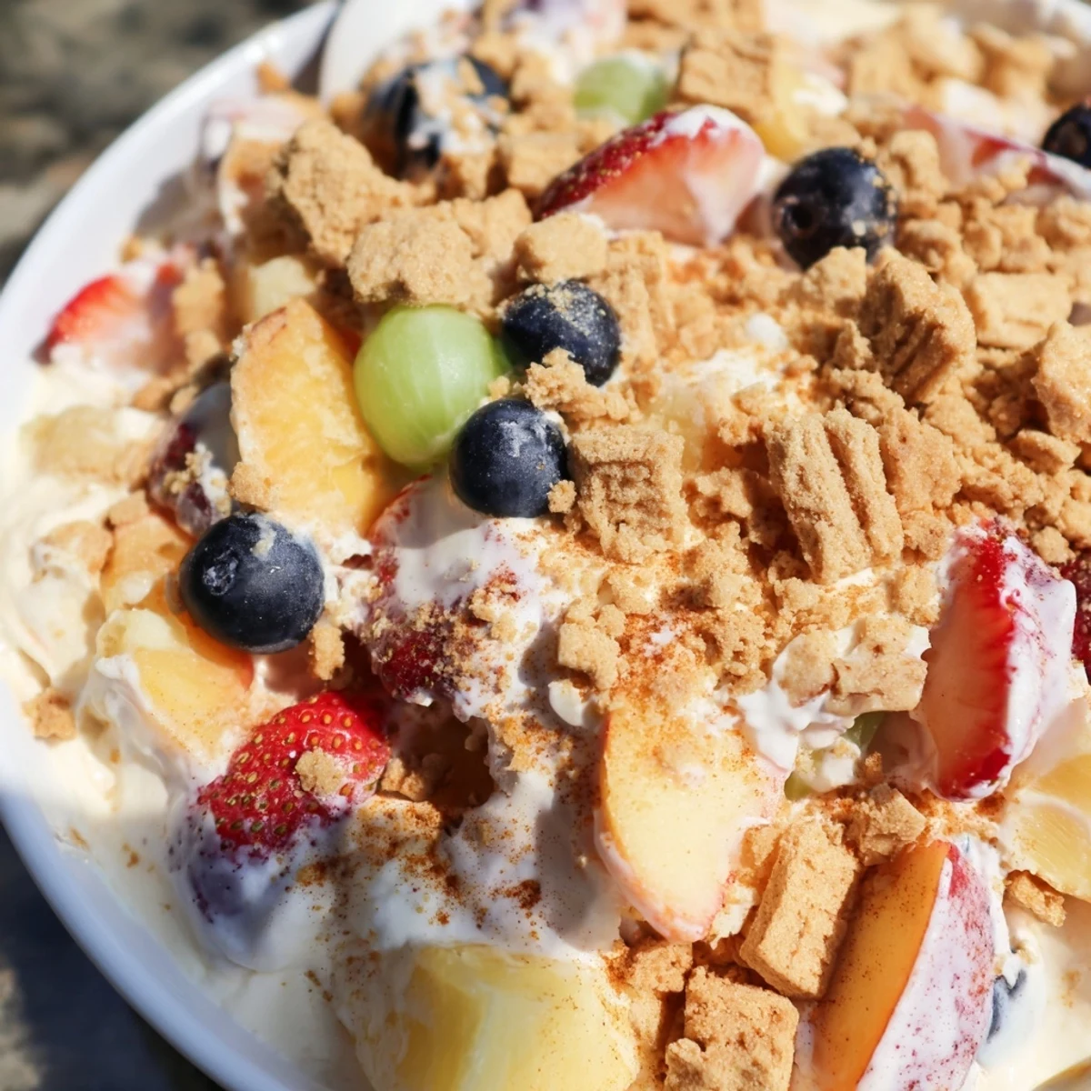Fresh peach cobbler cheesecake fruit salad topped with golden cinnamon crumble and ripe berries