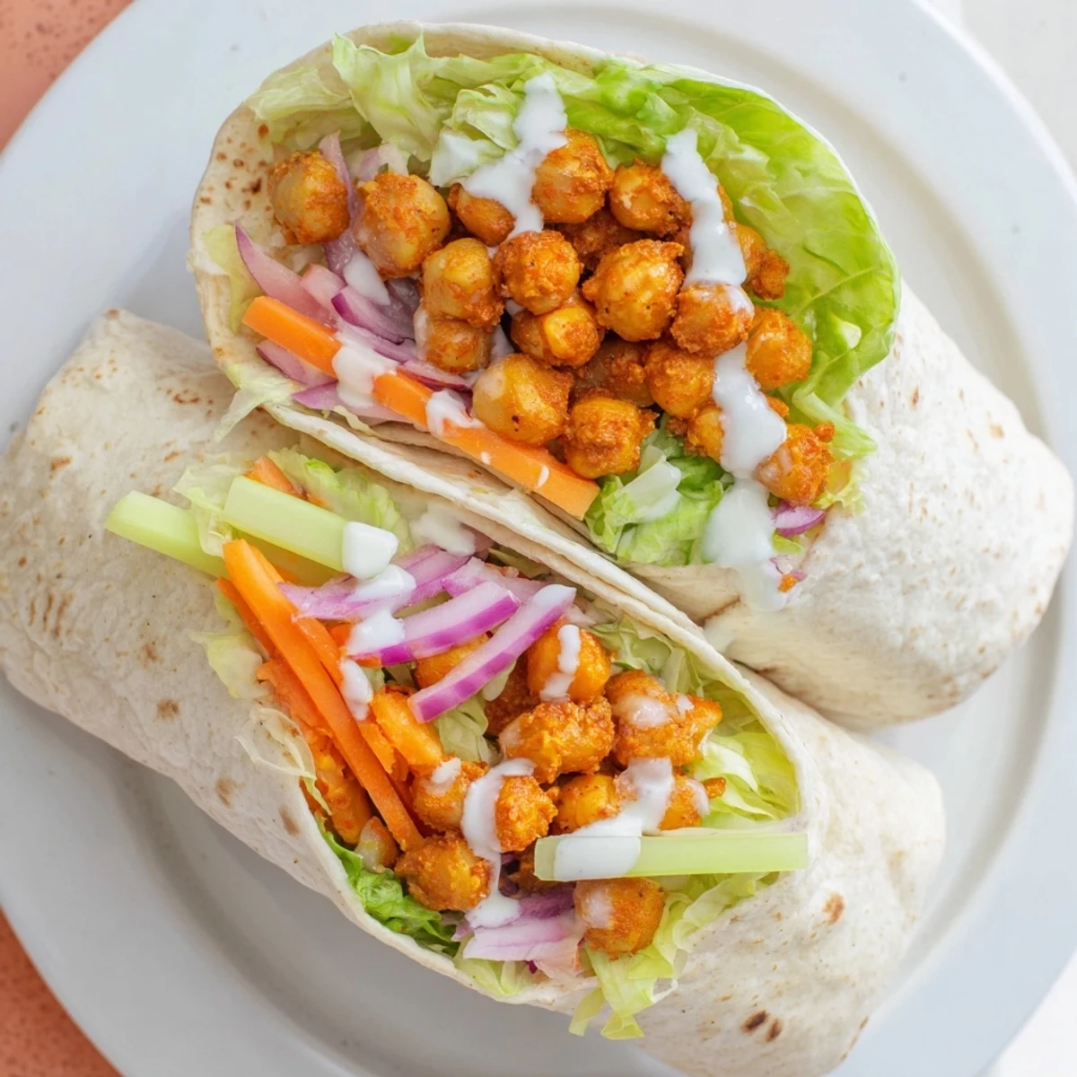 Flour tortilla rolled around seasoned buffalo chickpeas, julienned carrots, and tangy sauce for easy lunches