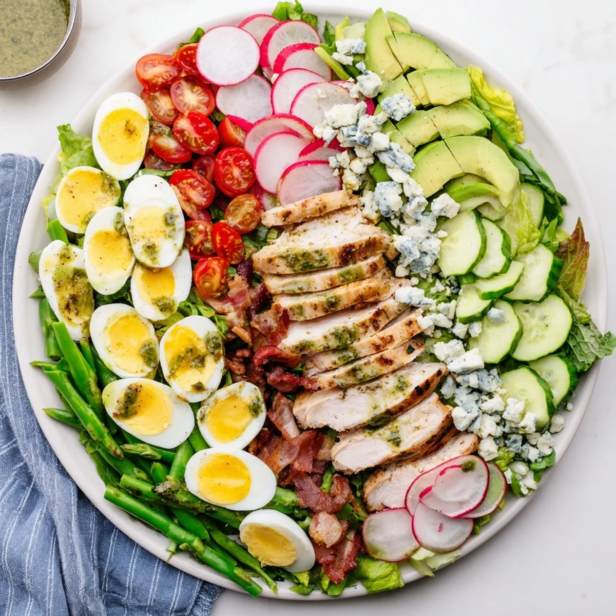 Fresh Spring Cobb Salad topped with grilled chicken, hard-boiled eggs, bacon, radishes, snap peas, and creamy blue cheese