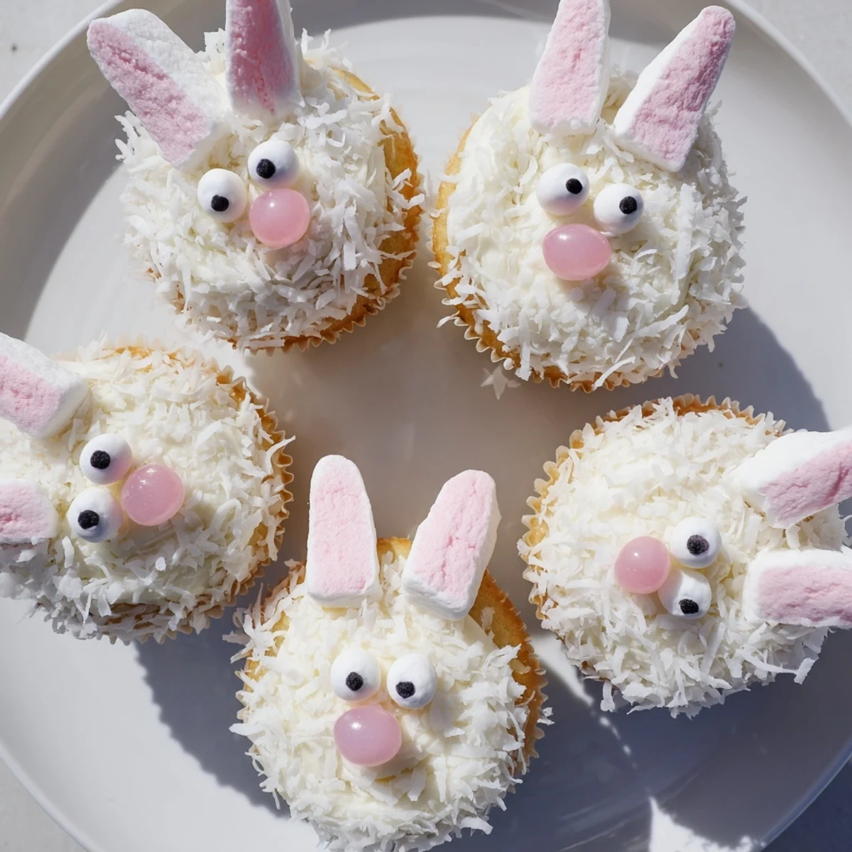 Adorable spring bunny cupcakes featuring buttercream frosting, coconut coating, and cute candy face decorations