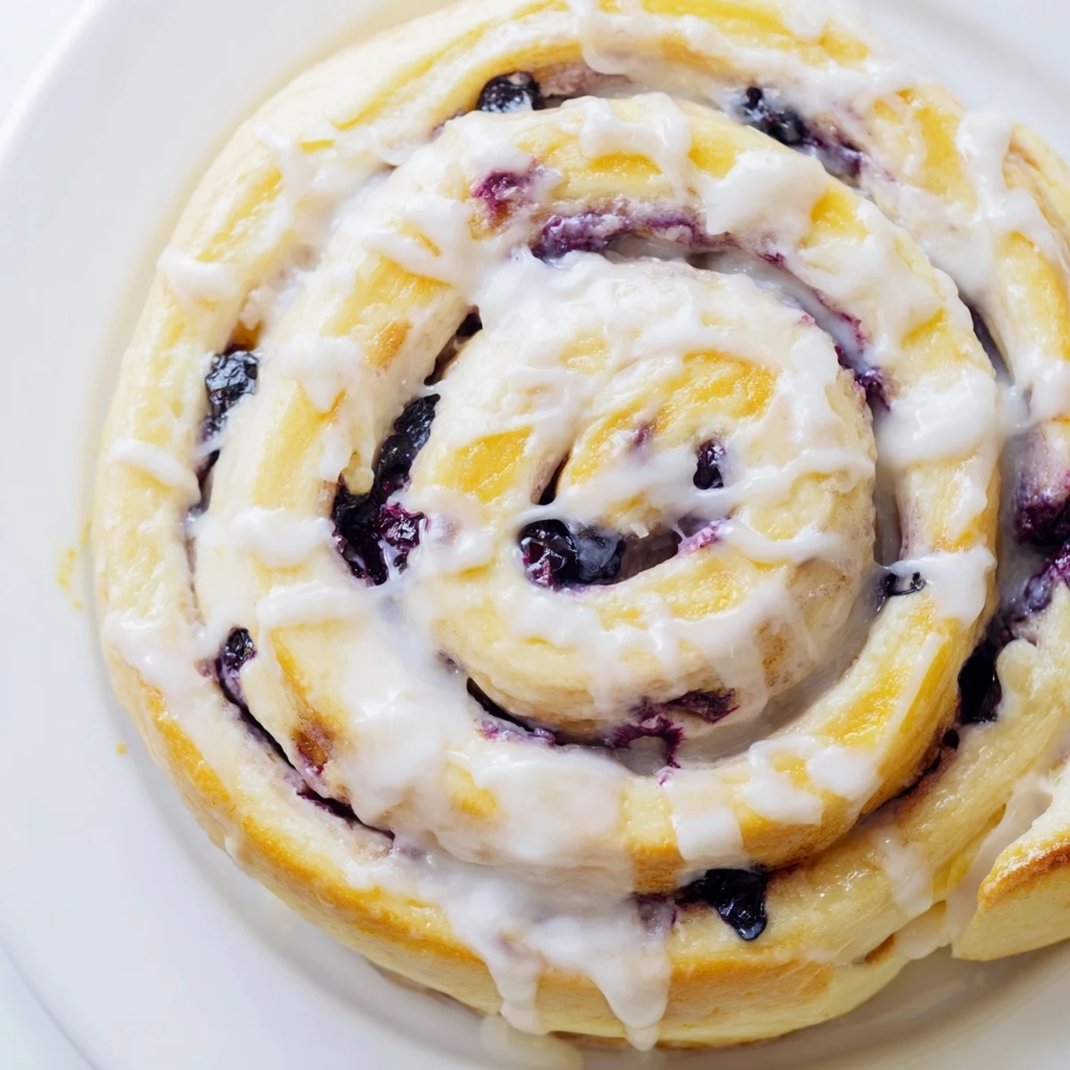 Soft swirled breakfast pastry bursting with blueberry filling and tangy lemon zest glaze