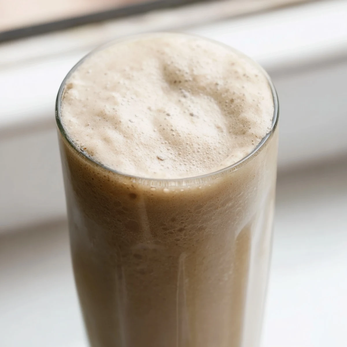 Creamy coffee smoothie in a glass topped with a sprinkle of cinnamon