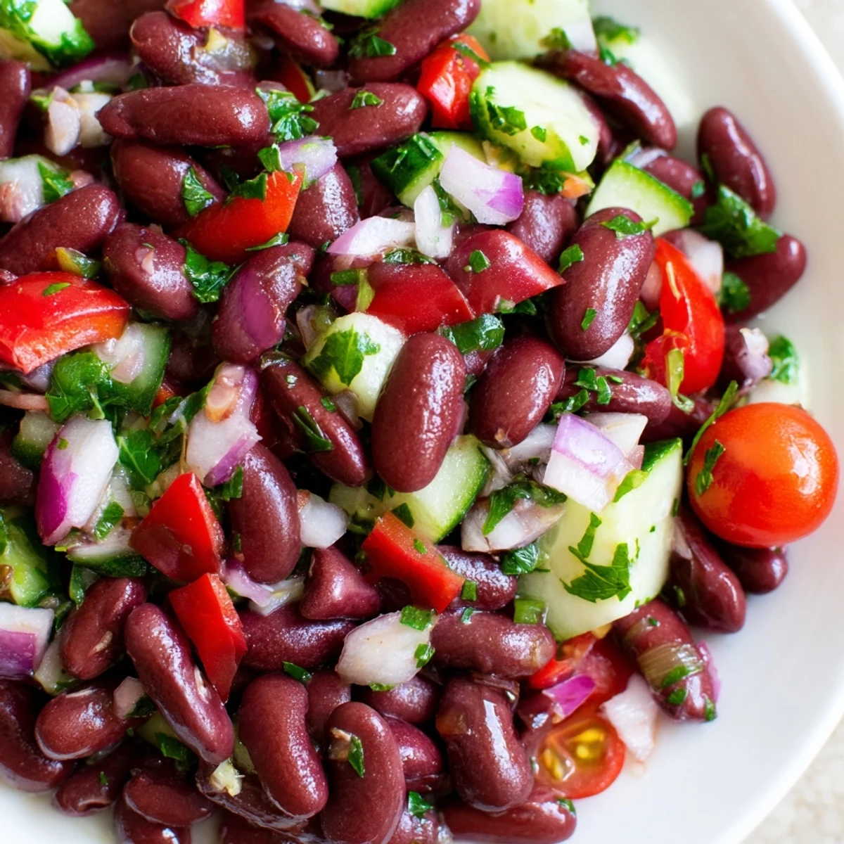 Colorful kidney bean salad in a white bowl with crisp vegetables and herbs