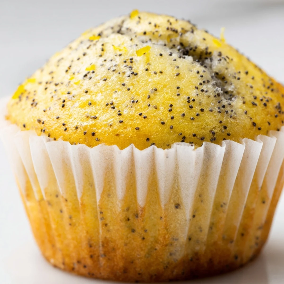 Golden lemon poppy seed muffins with domed tops fresh from the oven on a wire cooling rack.