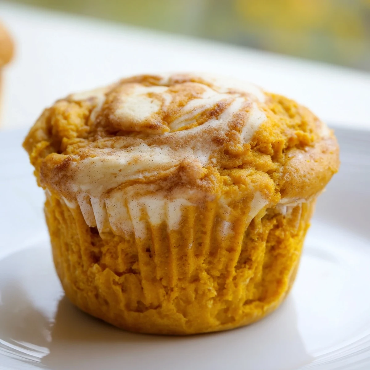 Warm Chai Pumpkin Cheesecake Muffins with swirled spiced cream cheese filling on rustic parchment paper.