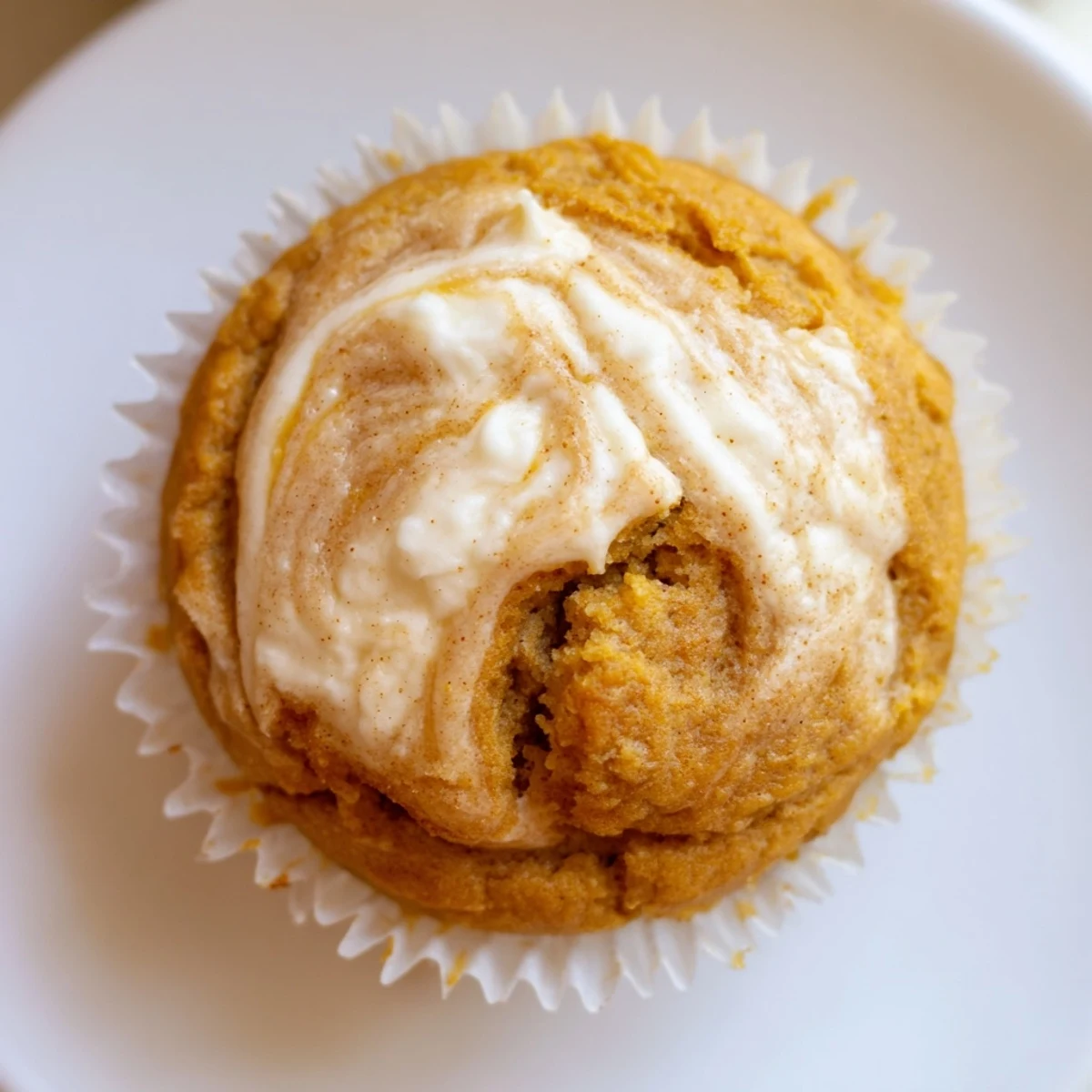 Golden pumpkin muffins crowned with creamy chai cheesecake swirls, fresh from the oven.