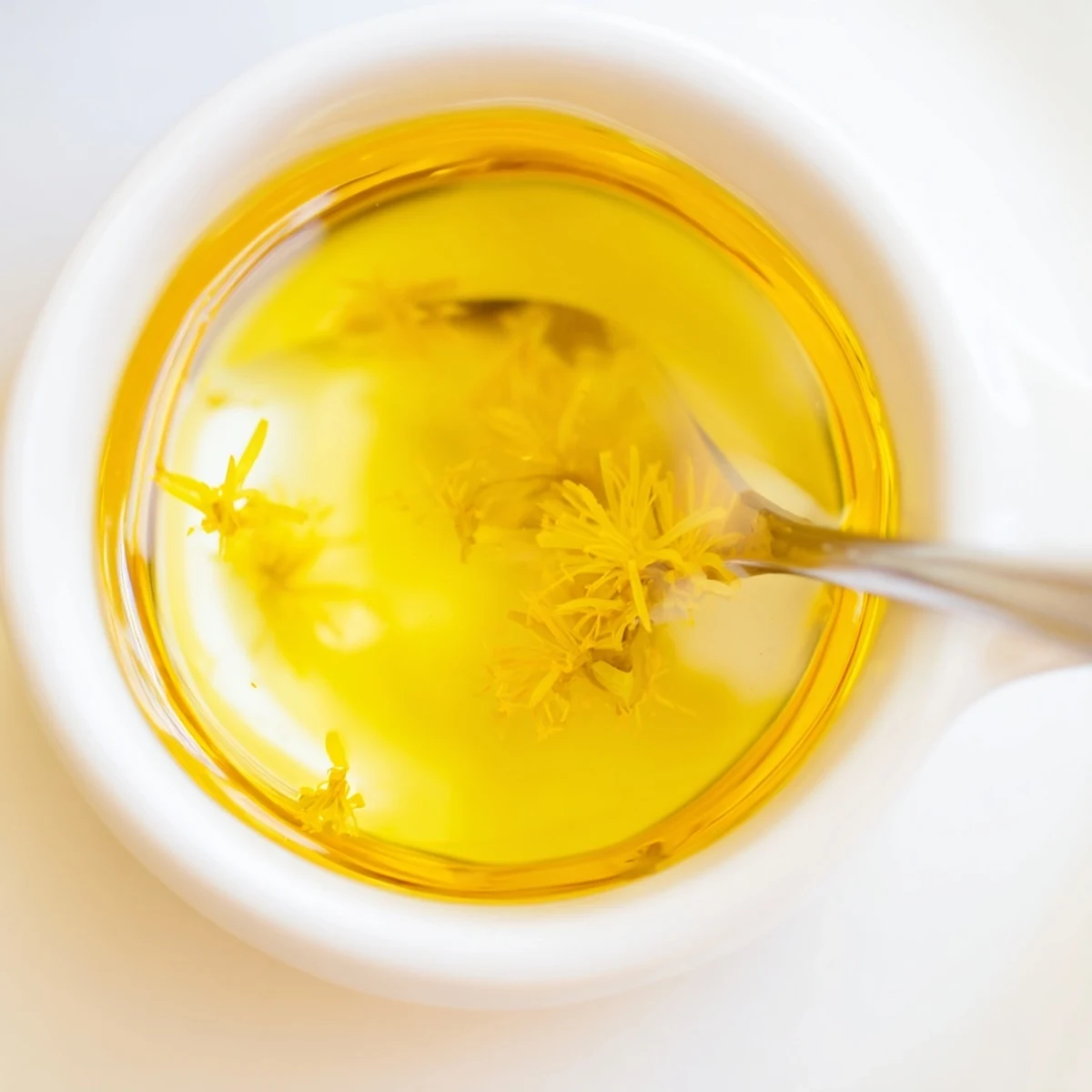 Golden homemade dandelion jelly glowing in a sunlit jar on a wooden table