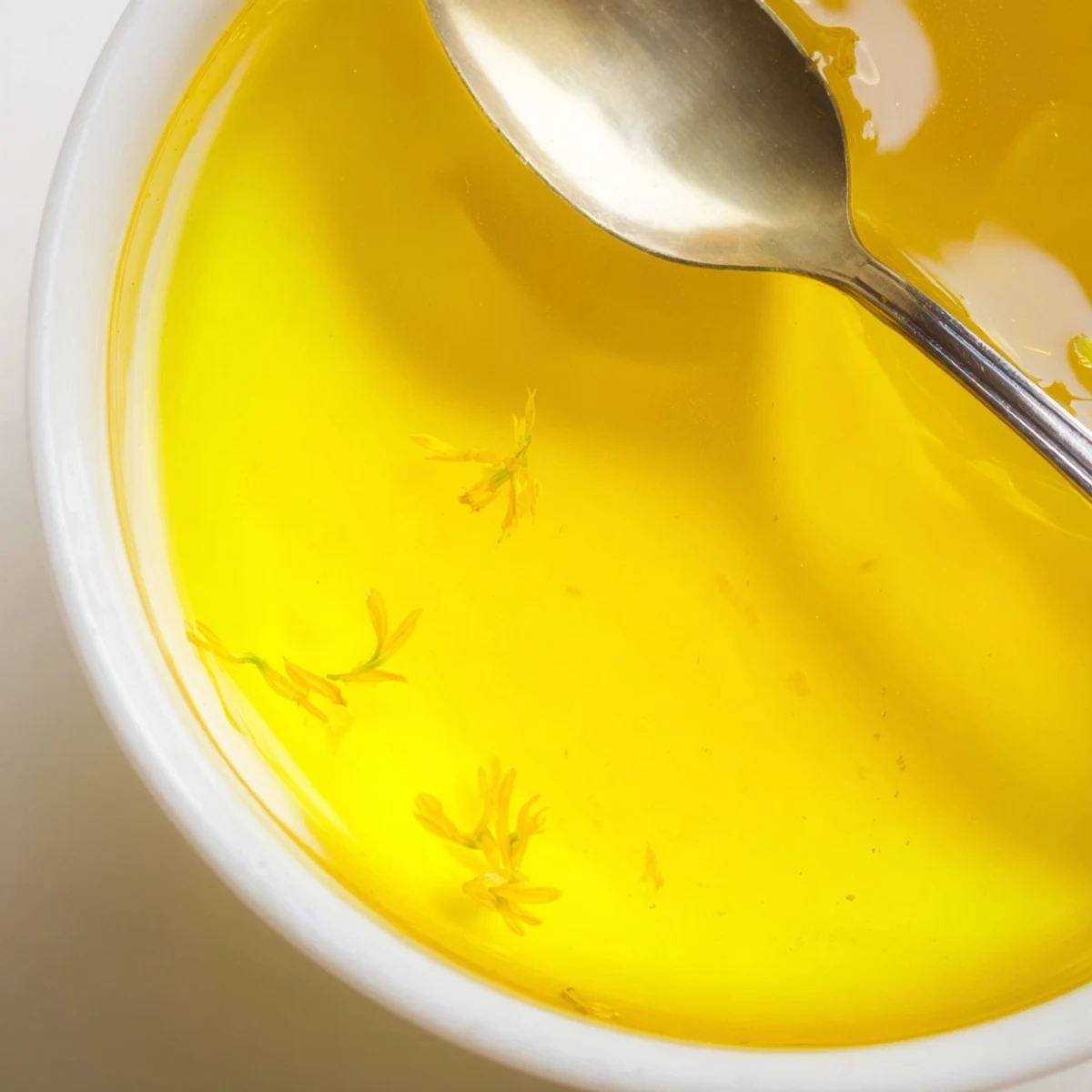 Homemade dandelion jelly spread on warm toast with fresh yellow petals scattered nearby