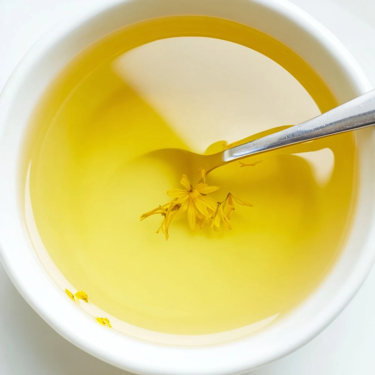 A small bowl of homemade dandelion jelly alongside a scone and soft cheese