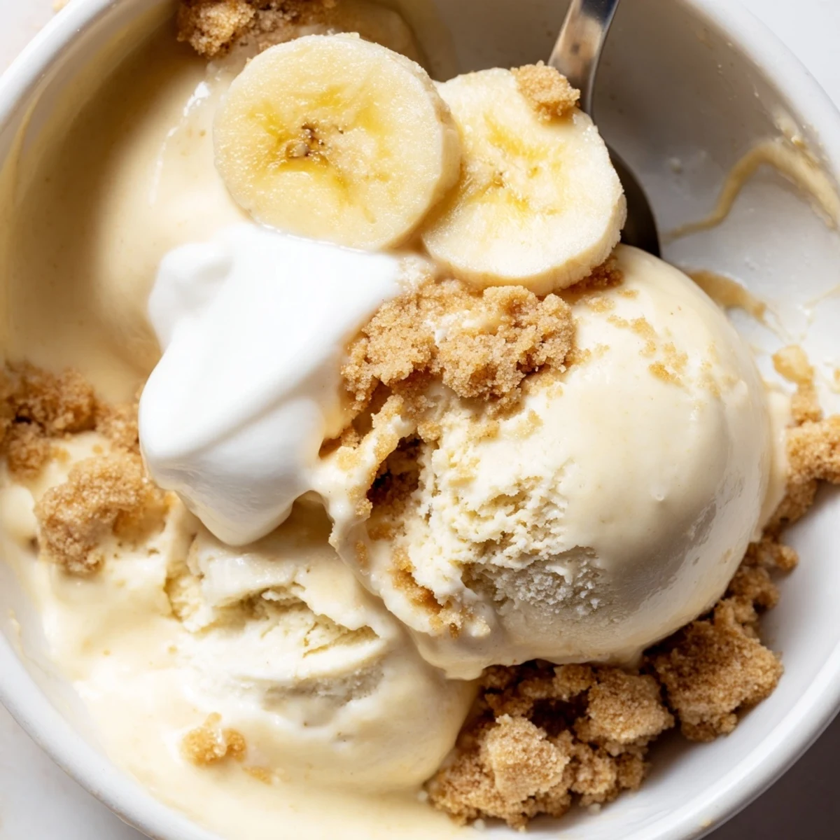 Scoops of Ninja Creami Banana Cream Pie Ice Cream topped with whipped cream.