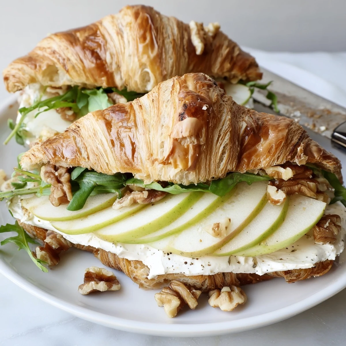 Flaky warm Apple Goat Cheese Croissant Sandwich drizzled with honey, crisp apple slices