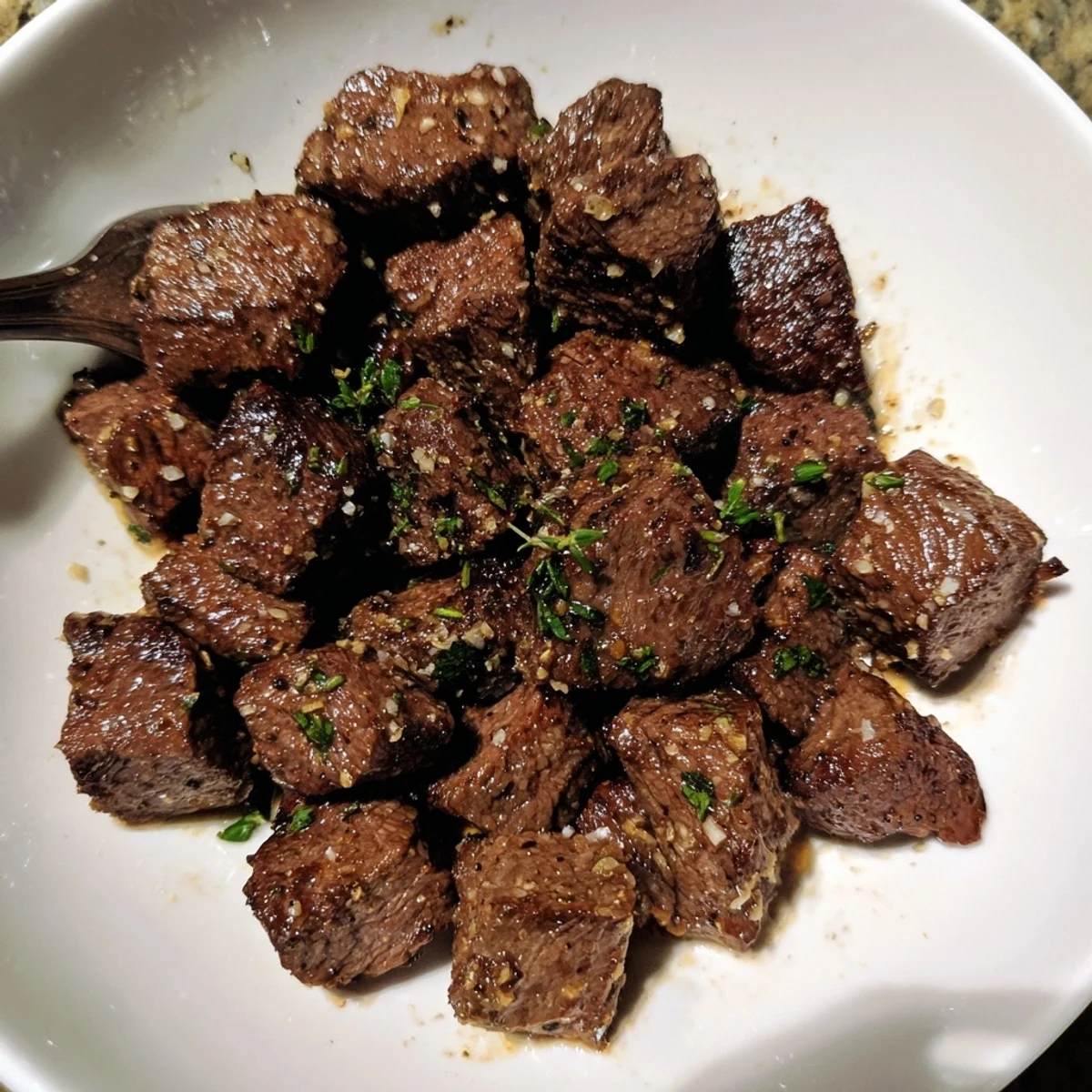 Close up skillet shot of Garlic Butter Steak Bites glistening with herbs