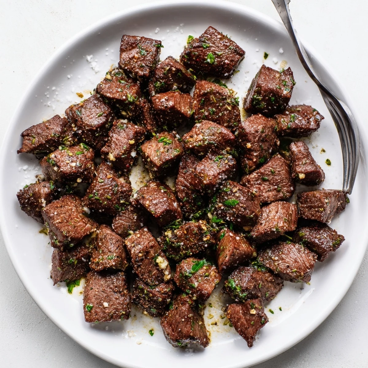 Quick Garlic Butter Steak Bites served over mashed potatoes, buttery sauce pooling