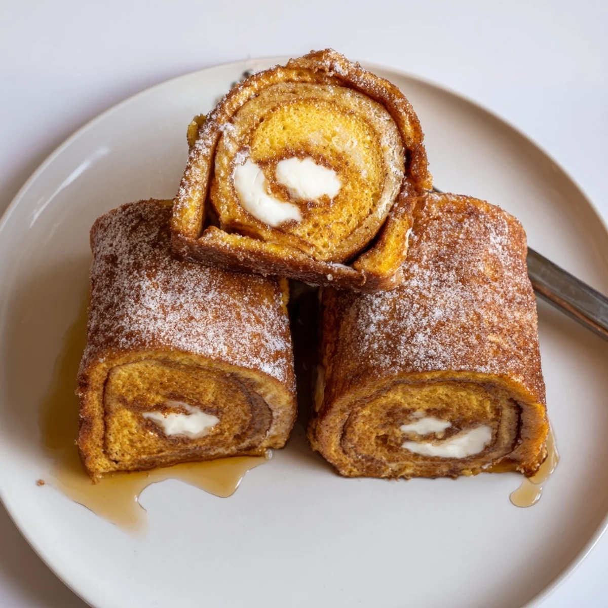 Cinnamon Roll French Toast Roll Ups served warm with maple syrup drizzle.