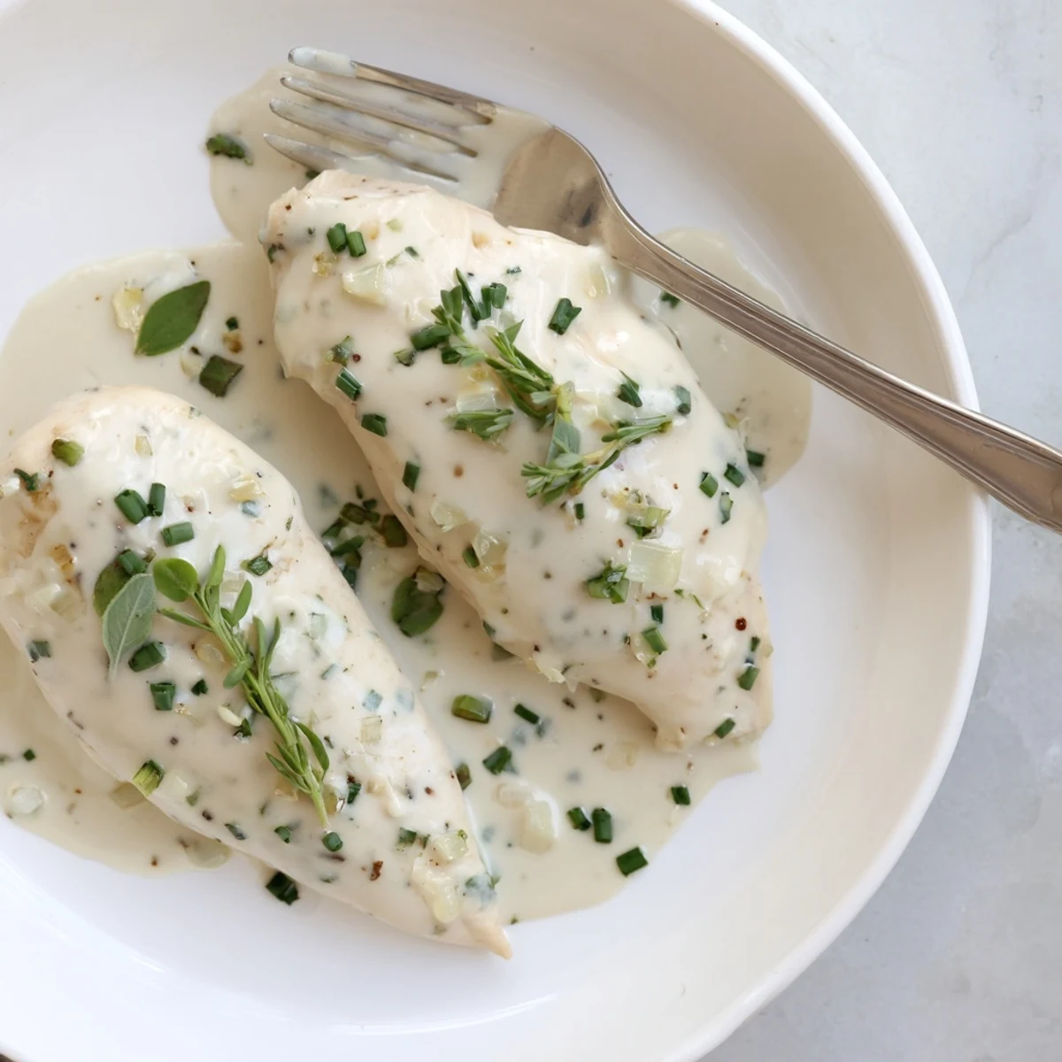 Tender juicy chicken pieces swimming in a luxurious cream sauce with aromatic chopped herbs