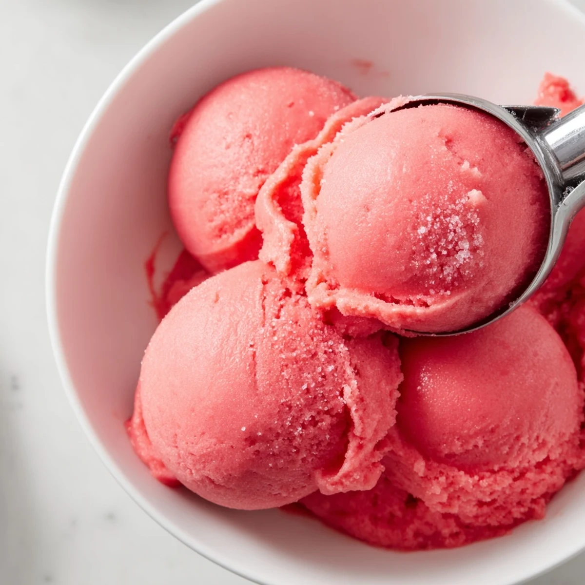 Vibrant frozen watermelon sorbet dessert served in decorative bowls with lime wedges on side